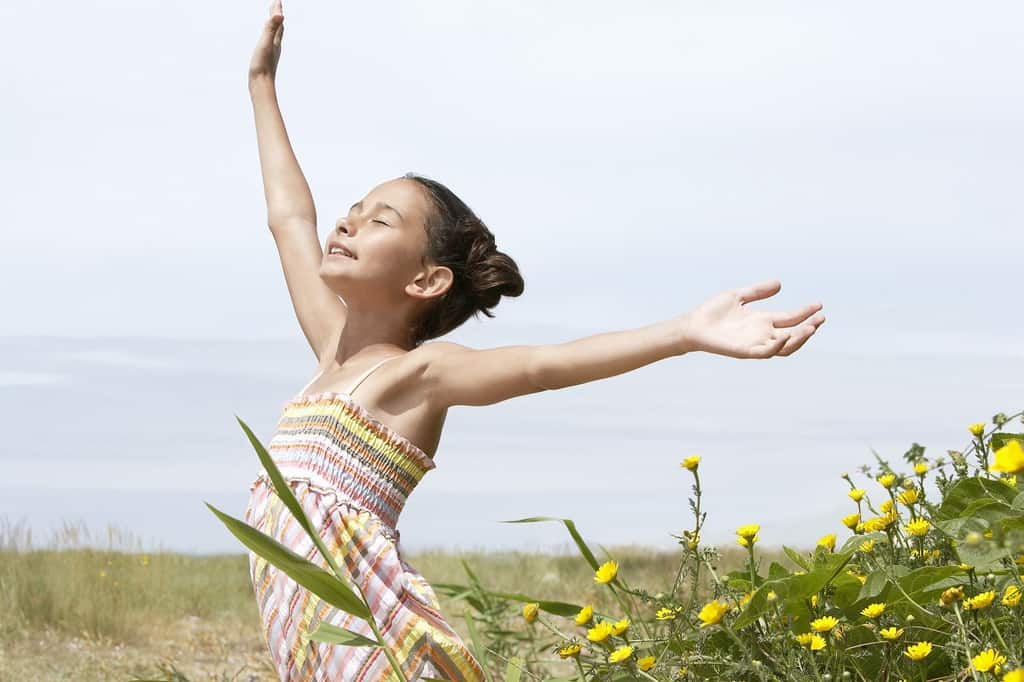 Pre-teen girl with arms raised