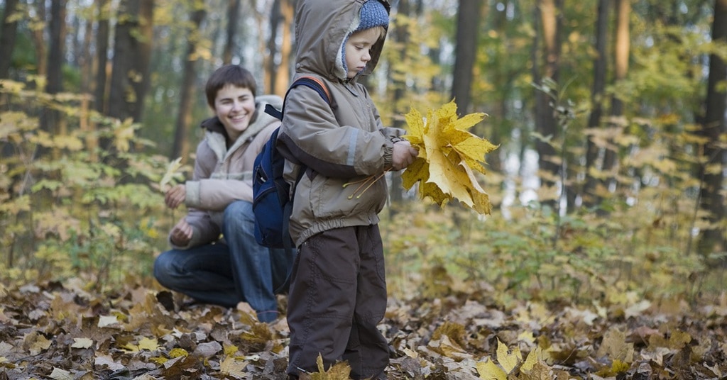 losing daylight - child playing in fall leaves